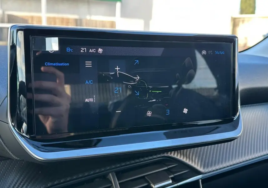 Écran tactile du système de climatisation dans l’habitacle d’une Peugeot 208 blanc, vue de face.