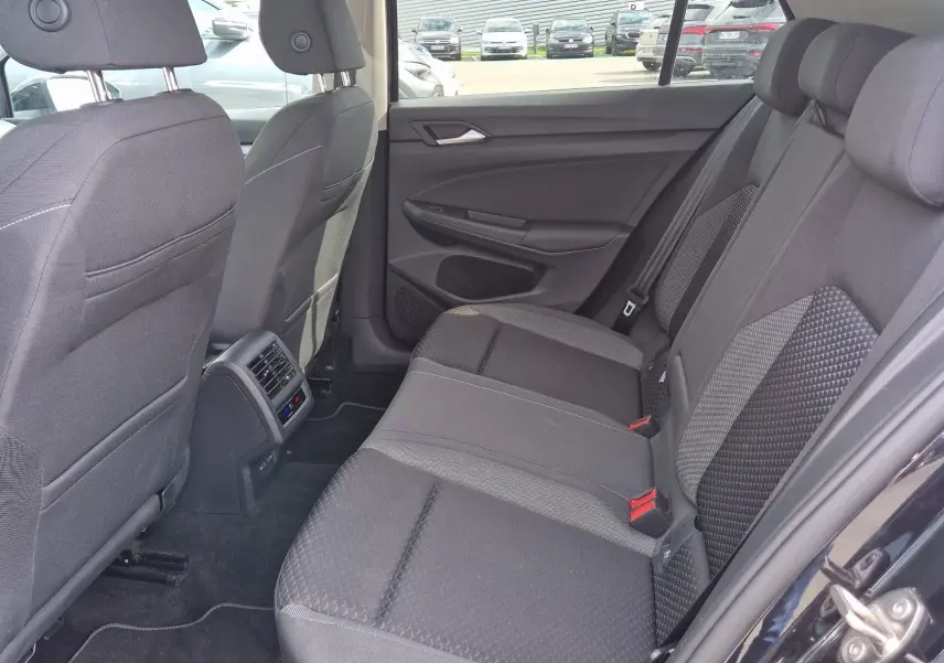 Vue intérieure côté droit sur la banquette arrière noire de la Volkswagen Golf 8 2023 avec porte ouverte.