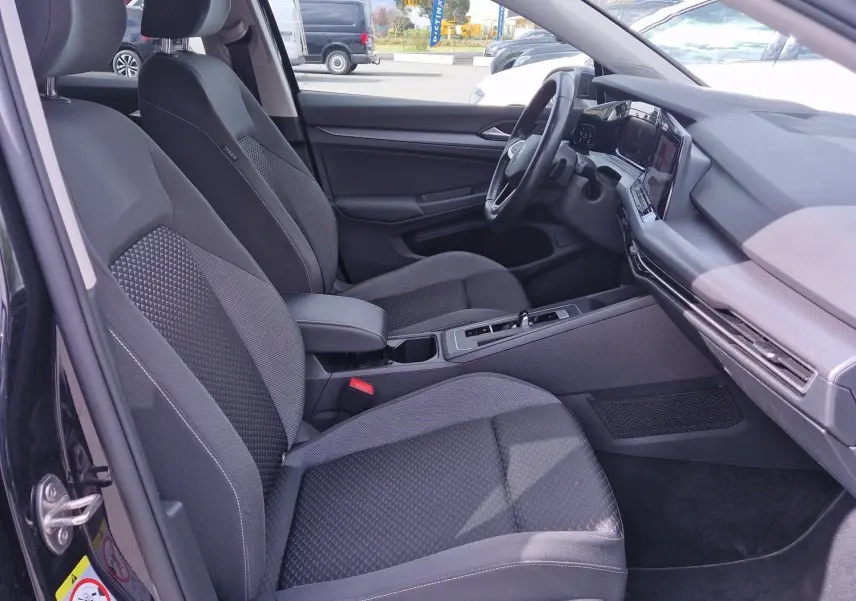 Vue intérieure côté gauche de la Volkswagen Golf 8 noire, montrant les sièges avant et le tableau de bord moderne.