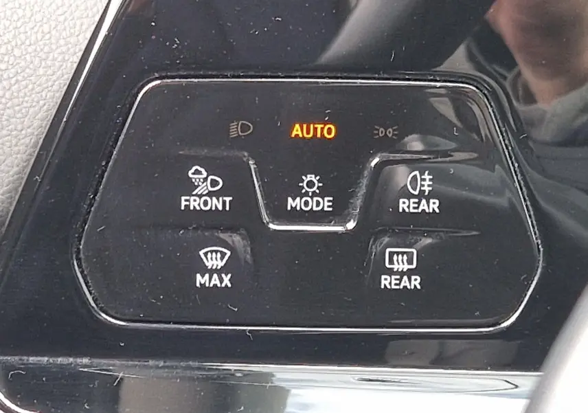 Gros plan sur les commandes de phares automatiques et essuie-glaces d’une Volkswagen Golf 8 noire, intérieur brillant.