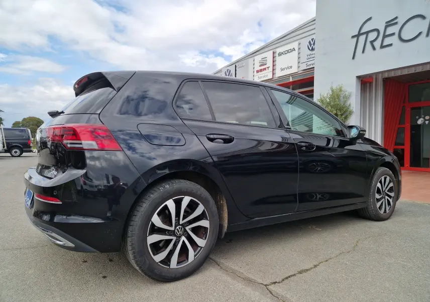 Vue 3/4 arrière droite d'une Volkswagen Golf 8 noire intense métal, avec jantes alliage distinctives et feux arrière LED.