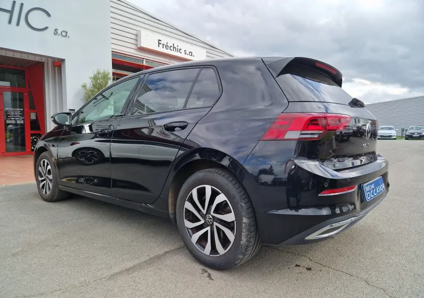 Vue 3/4 arrière droite d'une Volkswagen Golf 8 noire intense métal, avec feux arrière LED et jantes alliage distinctives.
