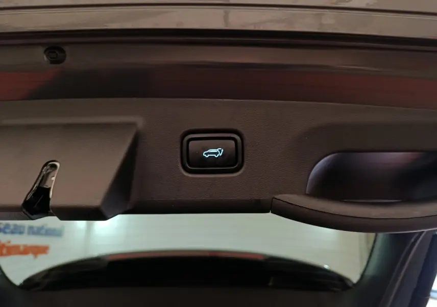 Bouton d'ouverture électrique du coffre sur la partie intérieure du hayon d'un Hyundai Tucson gris foncé.