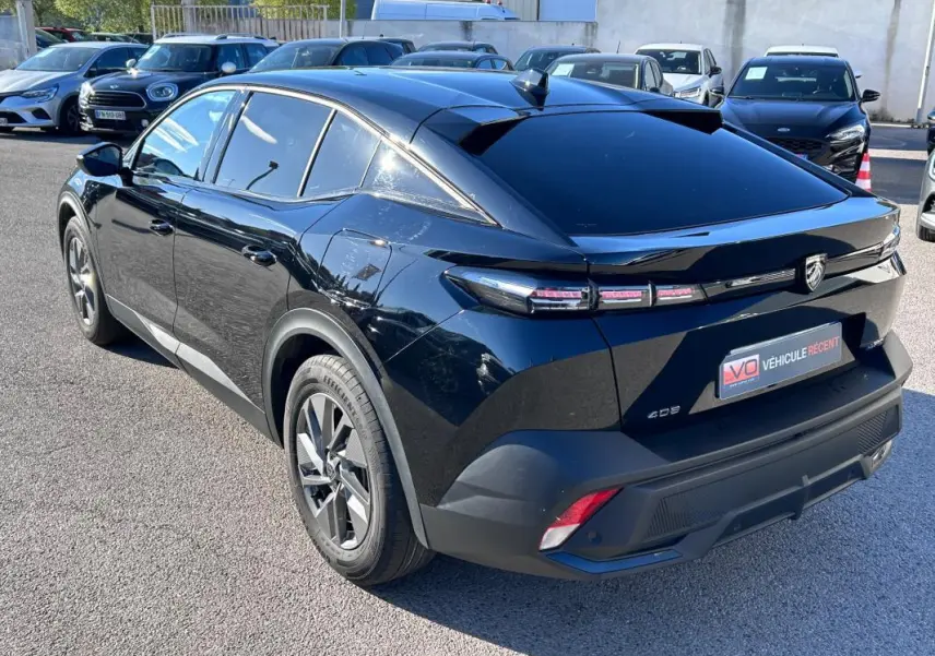 Vue 3/4 arrière droite d'une Peugeot 408 PHEV noire avec jantes alliage 17 pouces et feux arrière LED distinctifs.