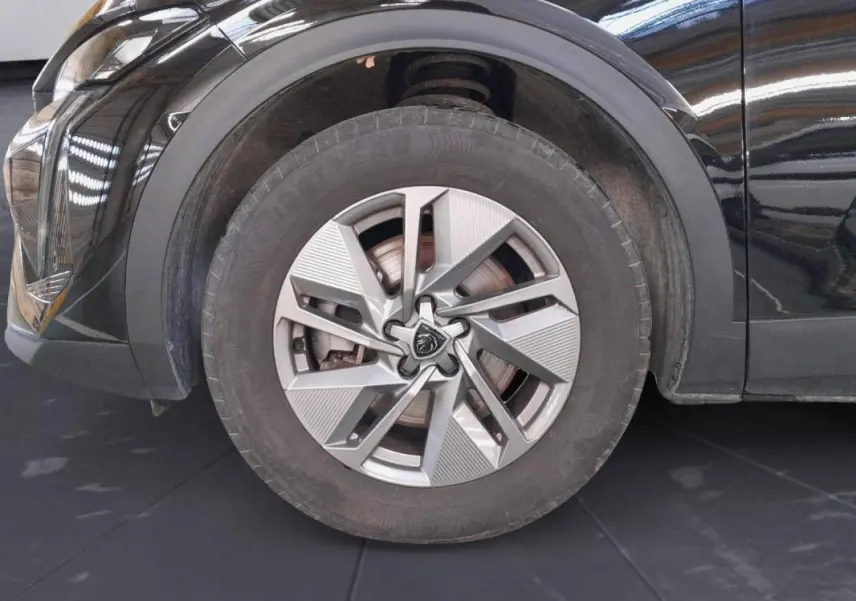 Gros plan sur la roue avant gauche de la Peugeot 408 PHEV 180 e-EAT8 Allure noire avec jante alliage 17 pouces.