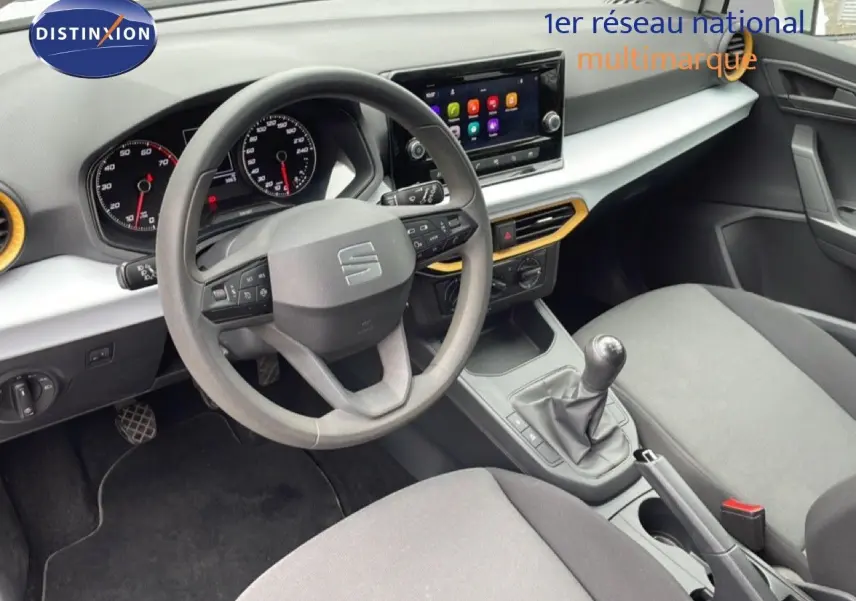 Vue intérieure côté conducteur de la SEAT Ibiza blanche, montrant le volant multifonction, la boîte manuelle et l’écran tactile central.