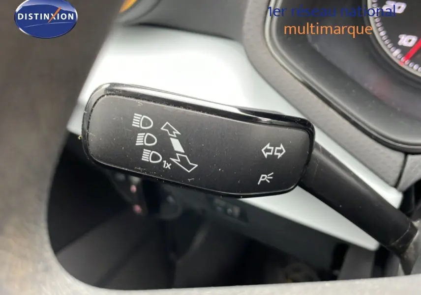 Gros plan sur la commande de clignotant à gauche du volant dans l’habitacle d’une SEAT Ibiza blanche.