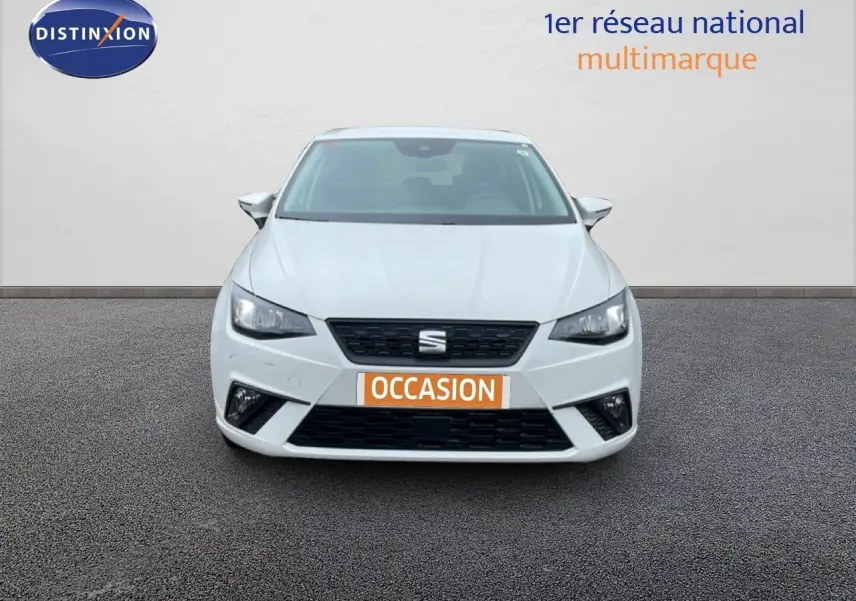 Vue avant d'une SEAT Ibiza blanche Candy avec calandre noire et plaque "OCCASION" orange sur un sol goudronné.