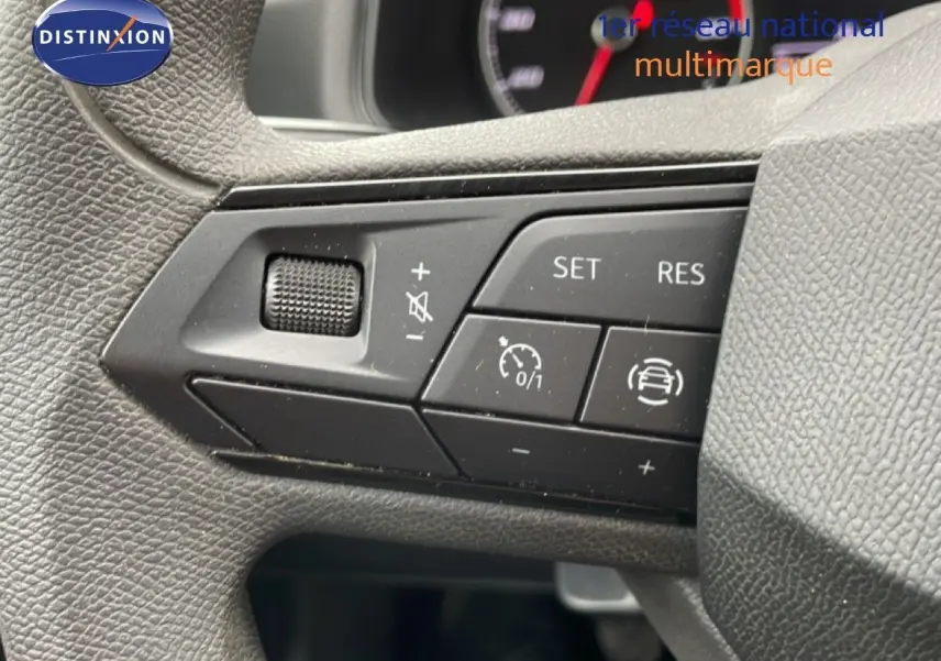 Gros plan sur les commandes au volant noir de la SEAT Ibiza blanche, mettant en valeur les boutons de régulateur de vitesse.