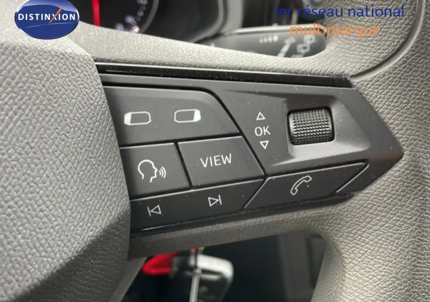 Gros plan sur les commandes au volant côté gauche de la SEAT Ibiza blanche, boutons multifonctions et molette de réglage.