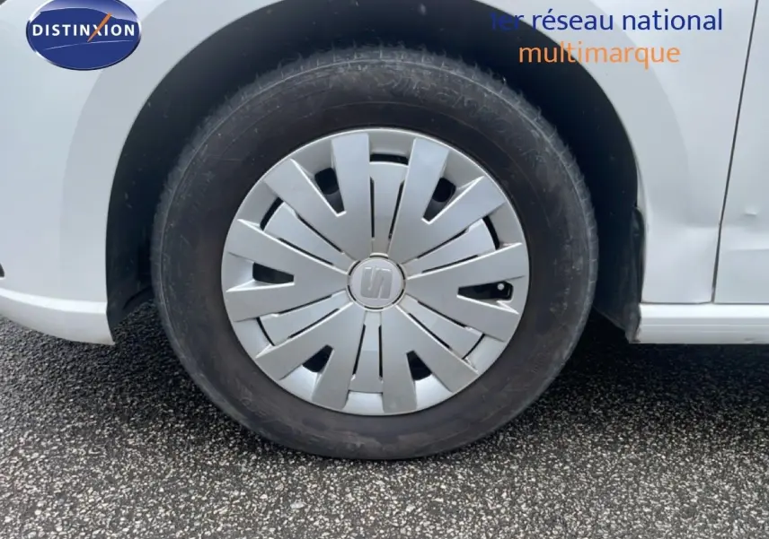 Gros plan sur la roue avant gauche d'une SEAT Ibiza blanche Candy, avec enjoliveur argenté au design moderne.