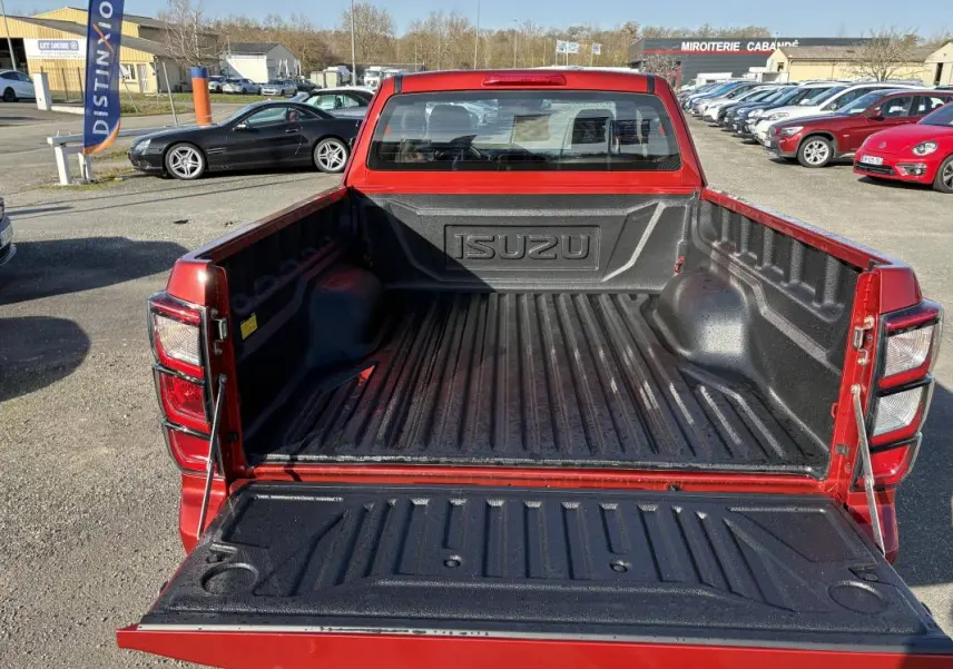 Vue arrière du pick-up Isuzu D-MAX orange 2026 avec benne ouverte et revêtement noir antidérapant.