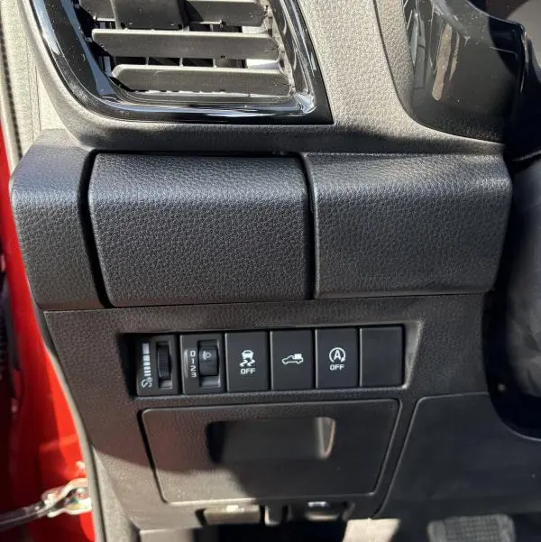 Vue rapprochée côté gauche du tableau de bord noir de l'Isuzu D-MAX orange 2026 avec commandes et sortie d'air.