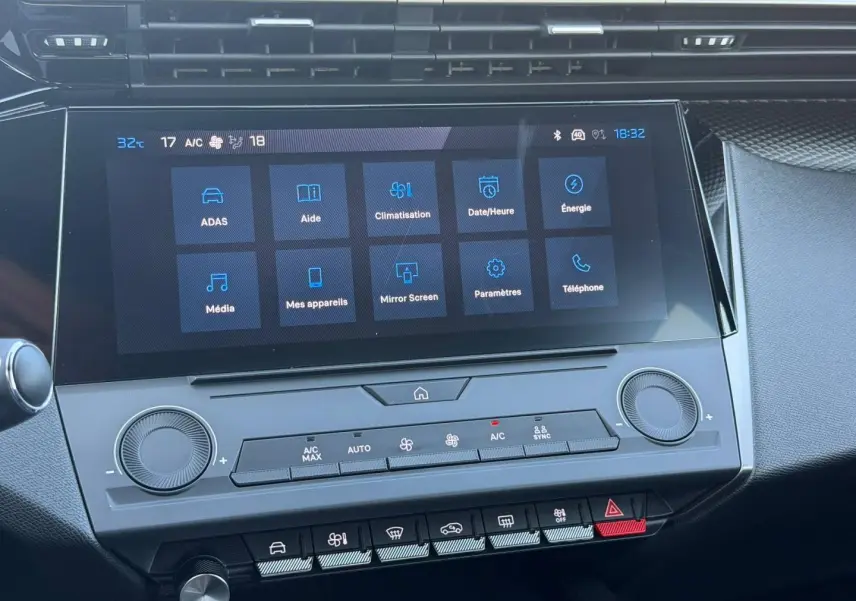 Gros plan sur l’écran tactile central et la console de climatisation de la Peugeot e-308 noire, intérieur moderne et épuré.