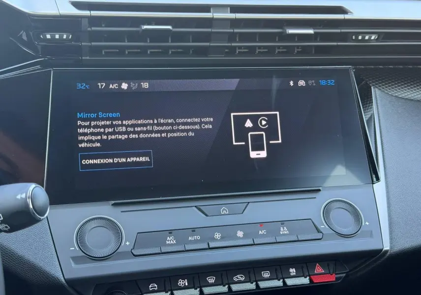 Vue rapprochée de l’écran tactile central et des commandes de climatisation de la Peugeot e-308 noire, intérieur moderne et épuré.