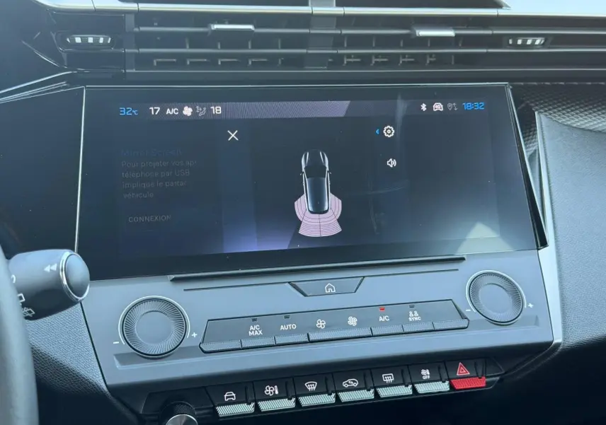 Vue rapprochée de l’écran tactile central et des commandes de climatisation de la Peugeot e-308 2025 noir Perla Nera.