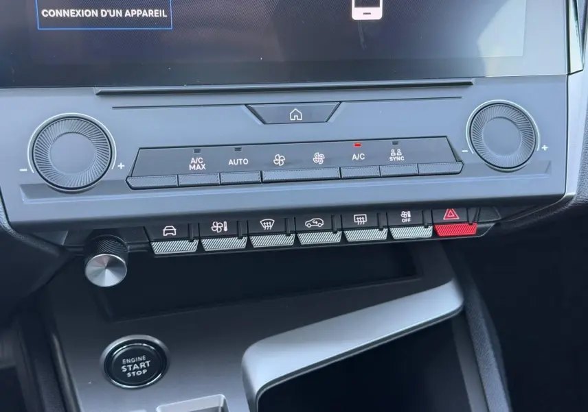 Vue rapprochée de la console centrale de la Peugeot 308 e-308 noire, montrant les commandes climatisation et bouton start/stop.