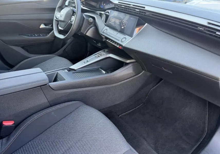 Intérieur avant droit de la Peugeot e-308 2025 noir, avec tableau de bord numérique et console centrale moderne.