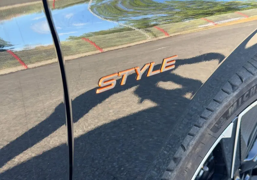 Gros plan sur l’inscription Style orange sur la carrosserie noire Perla Nera, près de la roue avant droite.