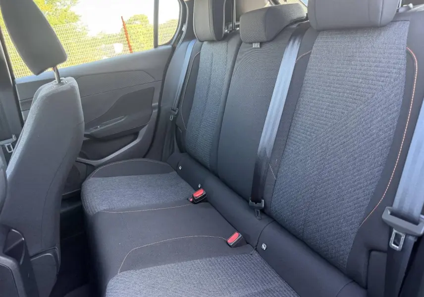 Vue latérale droite de la banquette arrière en tissu gris anthracite avec surpiqûres orange de la Peugeot 308 e-308 2025.