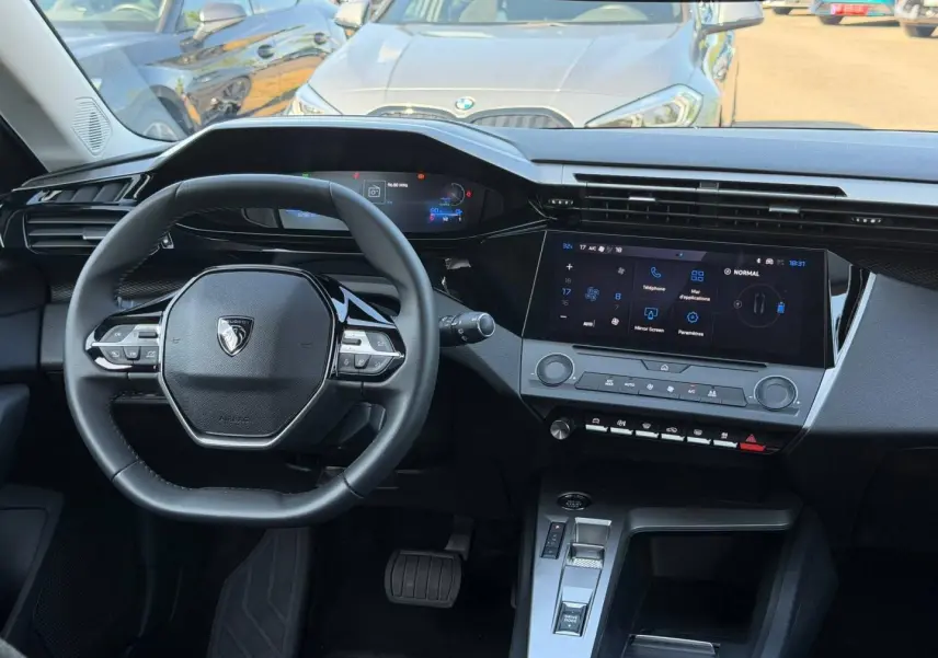 Vue intérieure avant du tableau de bord et volant noir de la Peugeot e-308 2025 avec écran tactile et commandes multifonctions.
