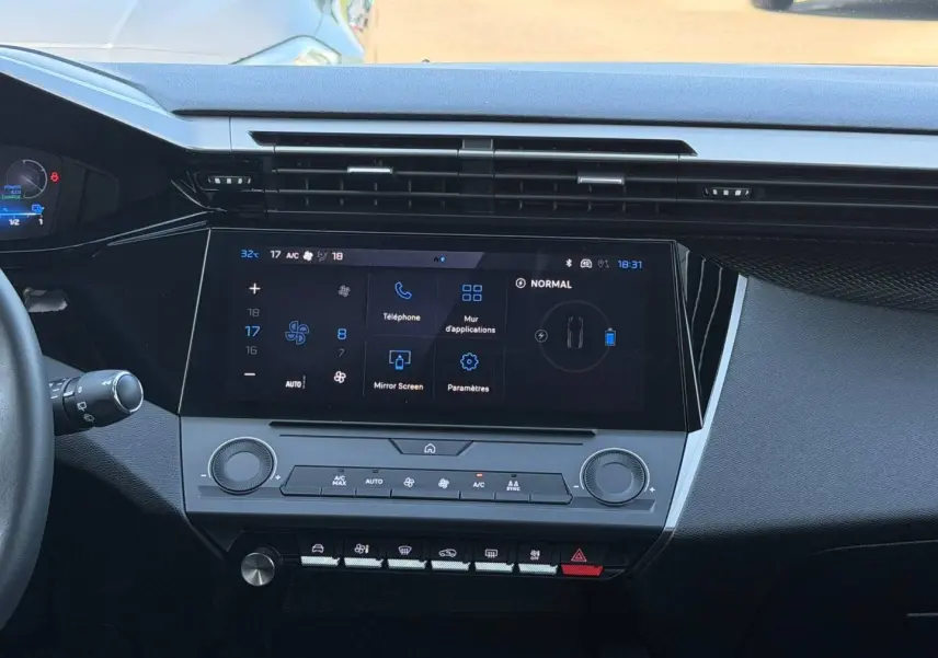 Vue intérieure centrée sur la console centrale tactile et les commandes de climatisation du Peugeot e-308 noir Perla Nera.