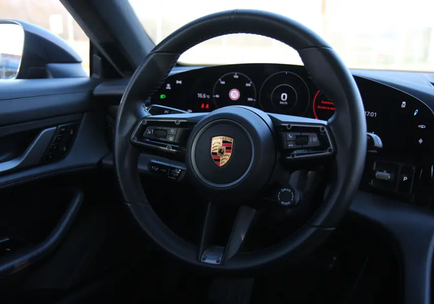 Vue intérieure centrée sur le volant cuir noir et le tableau de bord numérique du Porsche Taycan Turbo 2020.