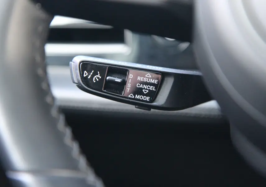 Gros plan sur la commande du régulateur de vitesse au volant d'une Porsche Taycan Turbo gris anthracite.