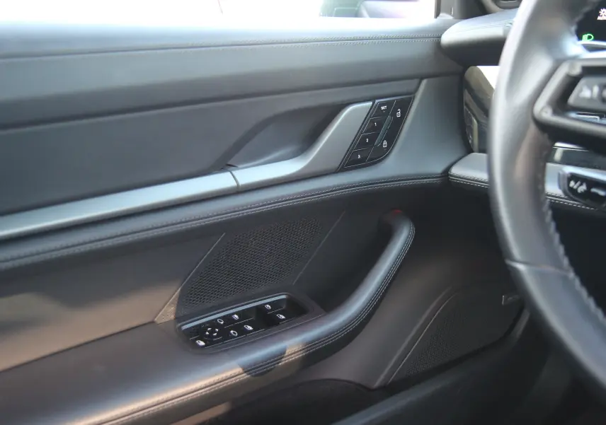 Détail de la porte côté conducteur du Porsche Taycan Turbo gris anthracite avec commandes de vitres et verrouillage.