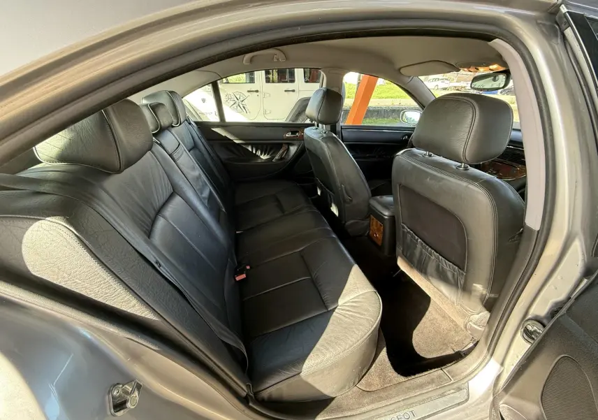 Vue intérieure arrière droite sur les sièges en cuir noir d'une Peugeot 607 gris 2003, avec seuils de porte Peugeot visibles.