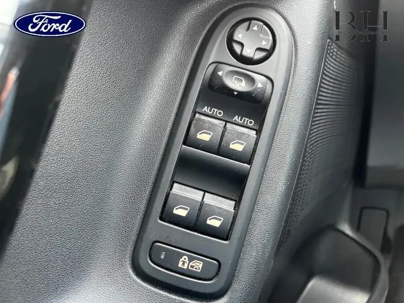 Gros plan sur les commandes électriques des vitres côté conducteur d'une Citroën C3 Bleu Encre, 2014.