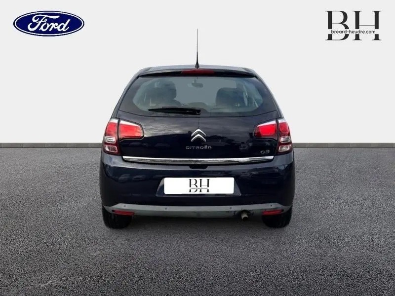 Vue arrière d'une Citroën C3 bleu encre 2014 avec feux rouges et logo chromé bien visibles.