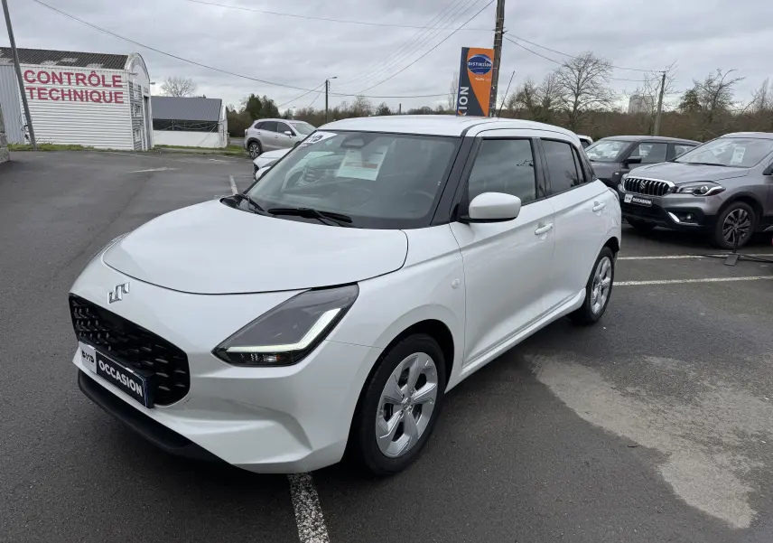 Vue 3/4 avant droite d'une Suzuki Swift 1.2 Privilège Hybrid blanche, avec calandre noire et jantes alliage.