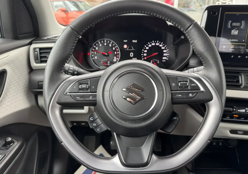 Vue centrée sur le volant noir du Suzuki Swift 1.2 Privilège Hybrid 2025 avec tableau de bord et écran tactile visibles.