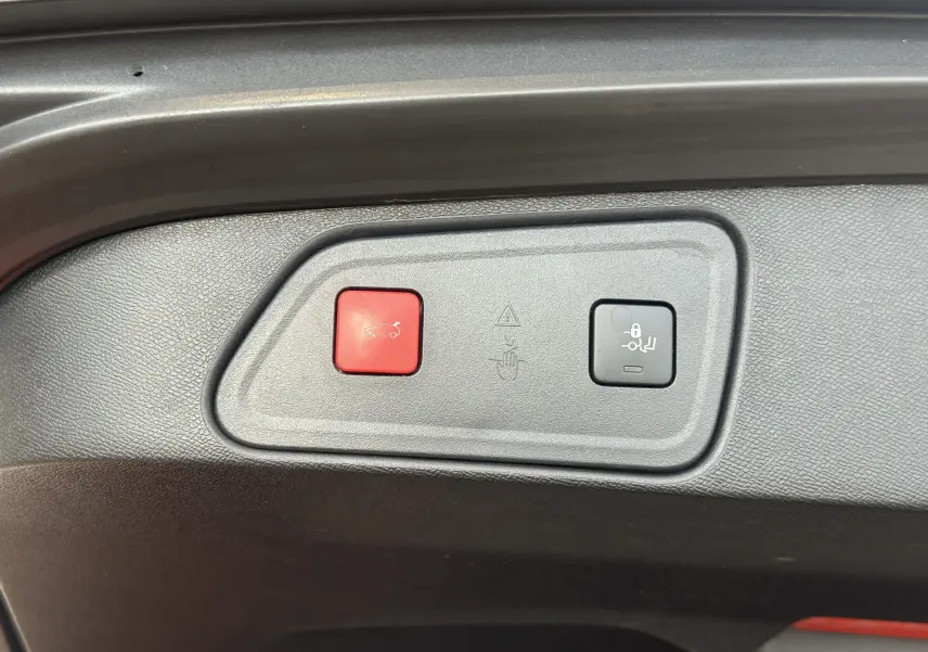 Gros plan sur les boutons d'ouverture et de verrouillage du coffre du Peugeot 3008 Hybrid rouge, version 2025.