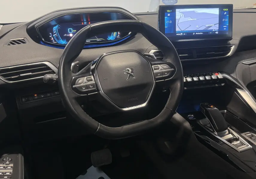 Vue intérieure centrée sur le volant et le tableau de bord numérique du Peugeot 3008 Hybrid rouge 2025.