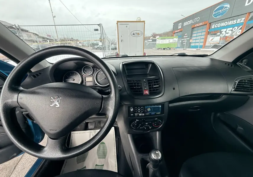 Vue intérieure arrière montrant la banquette arrière noire en tissu de la Peugeot 206+ bleue 3 portes.