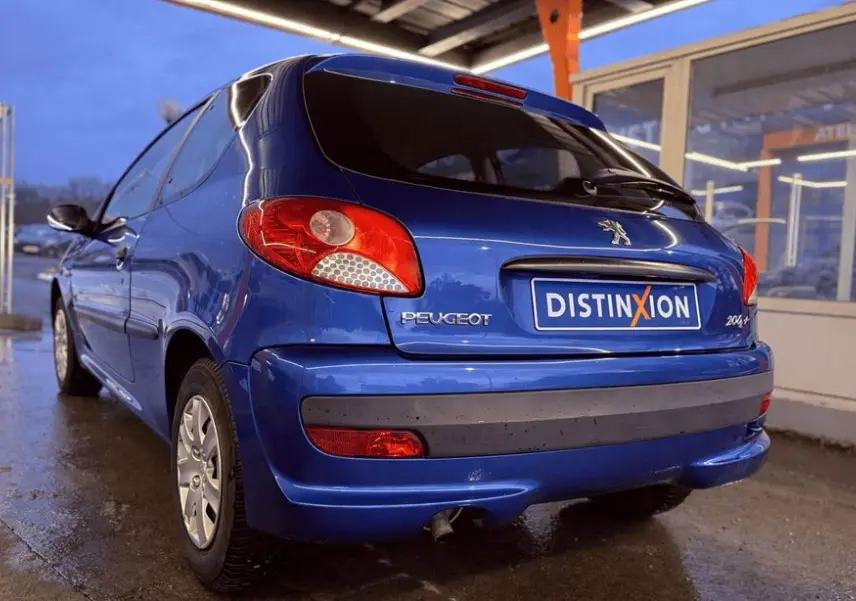 Profil latéral droit d'une Peugeot 206+ bleue à trois portes, avec poignées et protections noires visibles.