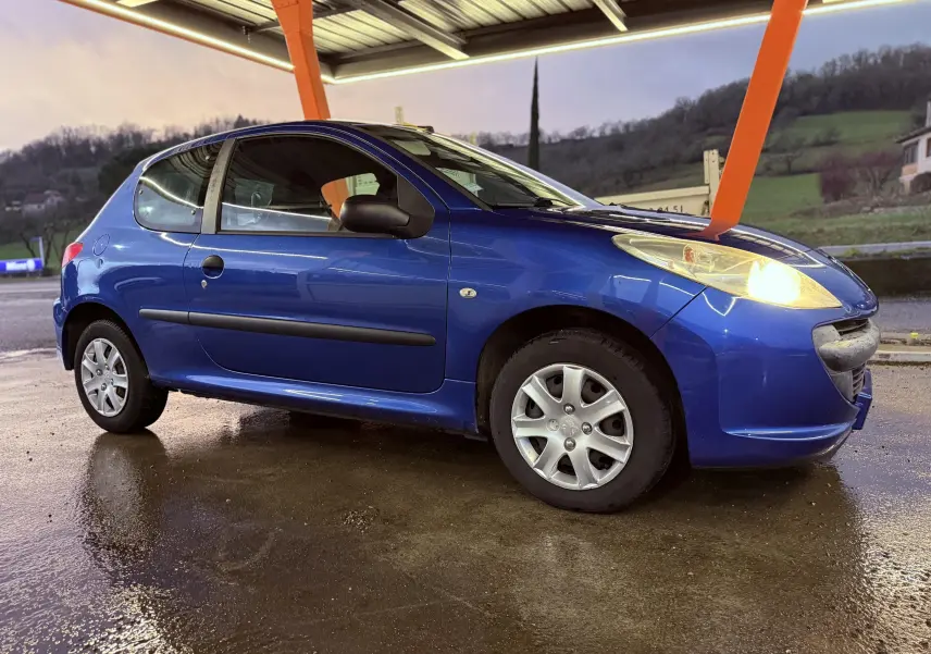 Peugeot 206+ bleu vue 3/4 arrière droit, compacte 3 portes avec feux arrière rouges et jantes alliage.