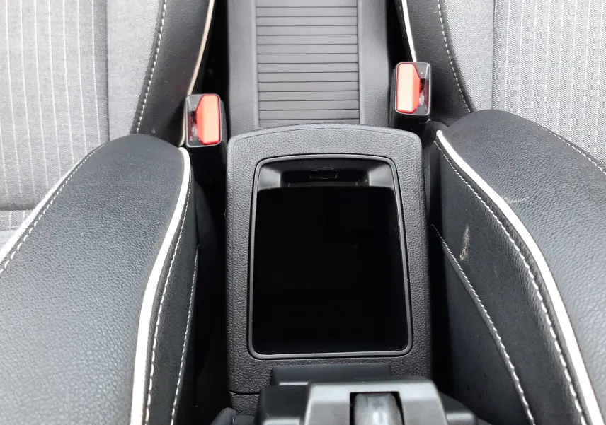 Vue plongeante sur la console centrale noire et les sièges gris à surpiqûres blanches de la Renault Clio V hybride.