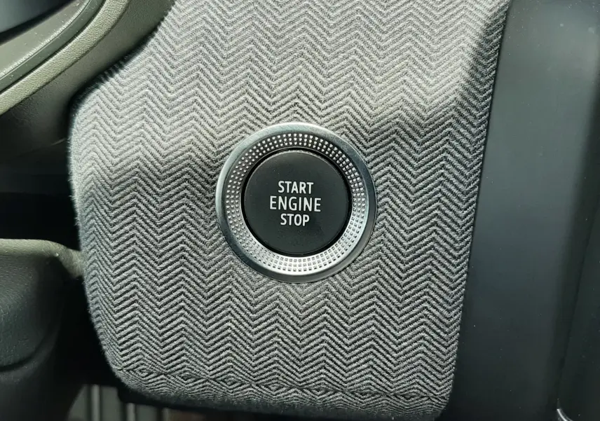 Bouton start/stop moteur sur tableau de bord en tissu gris à chevrons de Renault Clio V E-Tech hybride 2025.