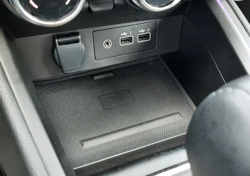 Vue rapprochée de la console centrale de la Renault Clio V rouge flamme, montrant les ports USB et commandes de climatisation.