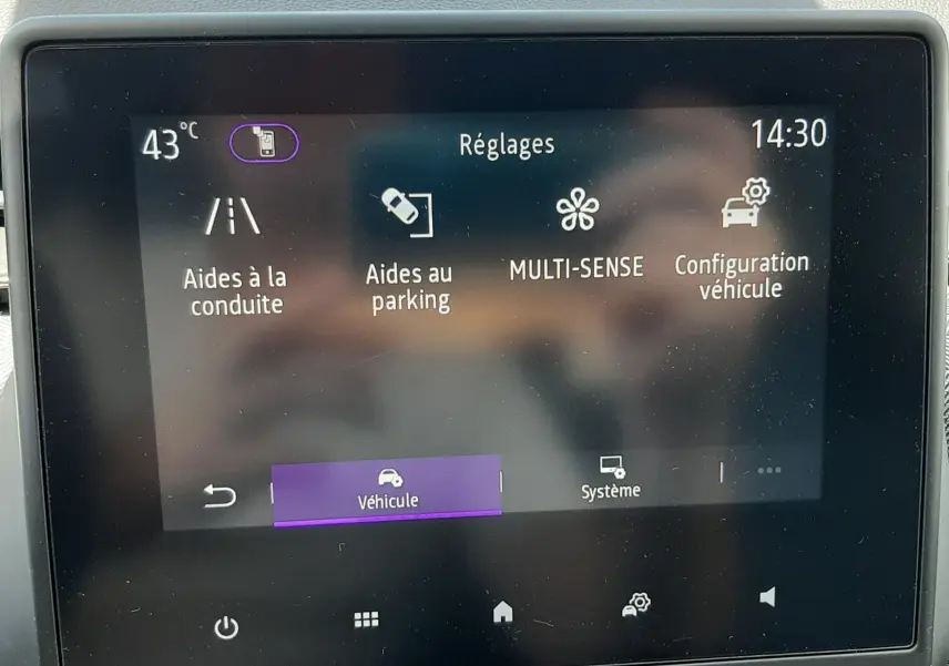 Écran tactile central de la Renault Clio V rouge flamme, affichant le menu Réglages avec options d'aides à la conduite et parking.