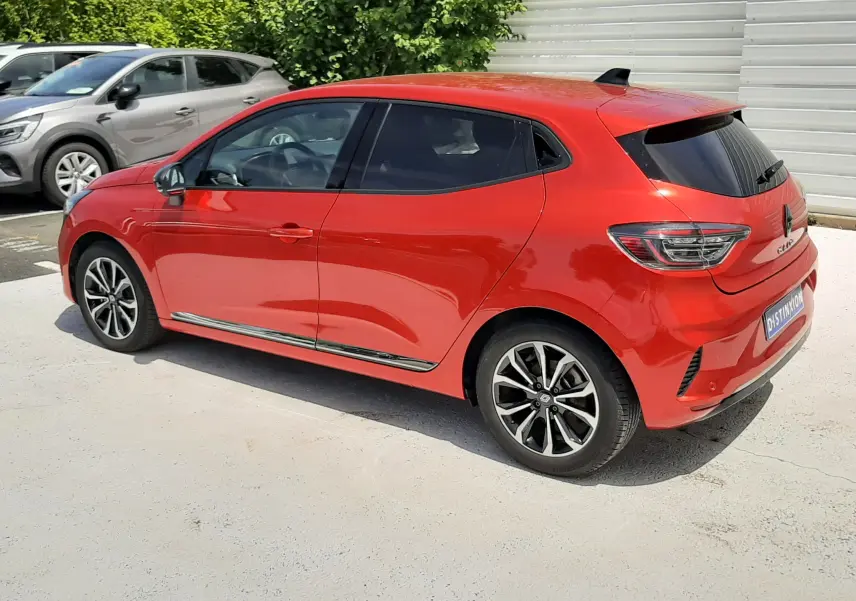 Renault Clio V E-Tech hybride rouge flamme, vue 3/4 arrière droit, jantes alliage et vitres teintées.