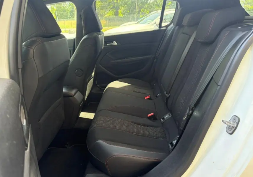 Vue intérieure arrière côté droit du Peugeot 308 GT-Line blanc, montrant les sièges arrière en tissu noir avec surpiqûres rouges.