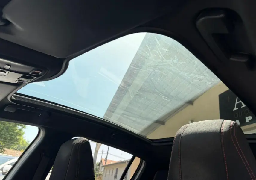 Toit panoramique en verre vu de l'intérieur sur Peugeot 308 GT-Line 2017 avec sièges noirs et surpiqûres rouges.