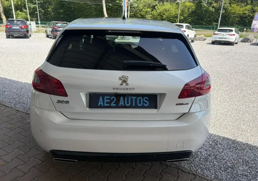 Vue arrière d'une Peugeot 308 GT-Line blanche de 2017, avec feux arrière rouges et double sortie d'échappement.