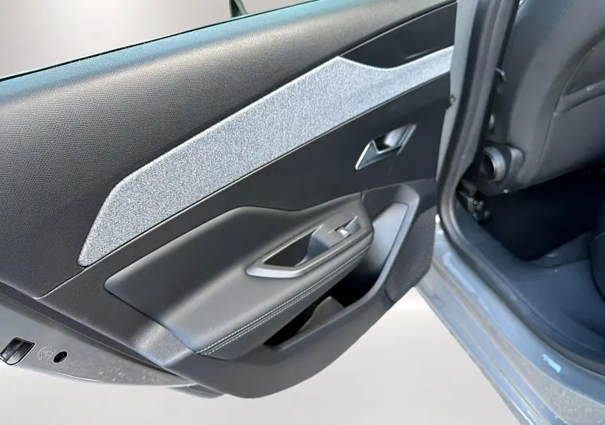 Vue rapprochée de la porte arrière gauche gris selenium de la Peugeot 308 2025 avec garniture textile et plastique noir.