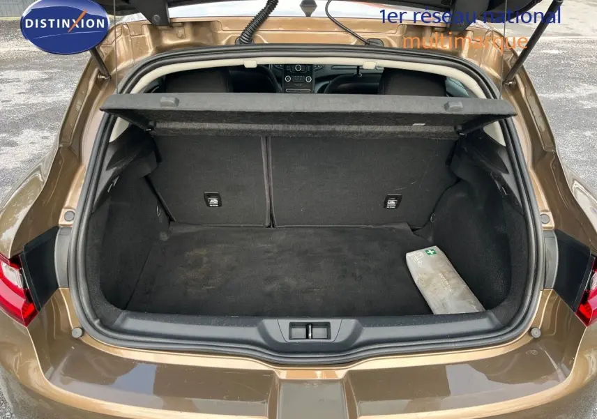 Coffre ouvert vu de l'arrière d'une Renault Mégane IV brun Capuccino, montrant un espace de rangement propre avec cache-bagages.