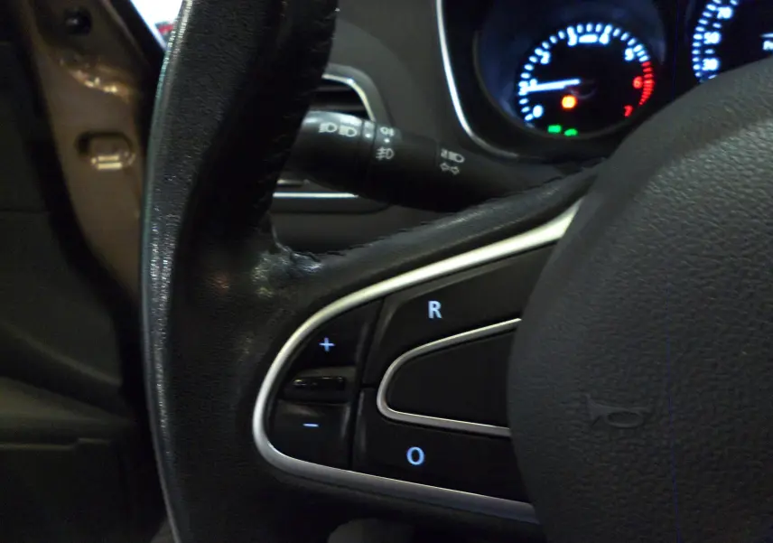 Vue intérieure centrée sur le volant noir d’une Renault Mégane IV brun capuccino, avec tableau de bord et console centrale visibles.